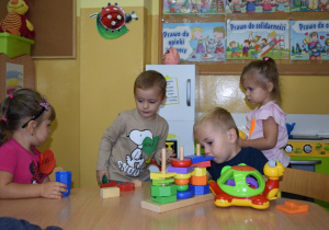 Dzieci bawią sie przy stoliku zabawkami